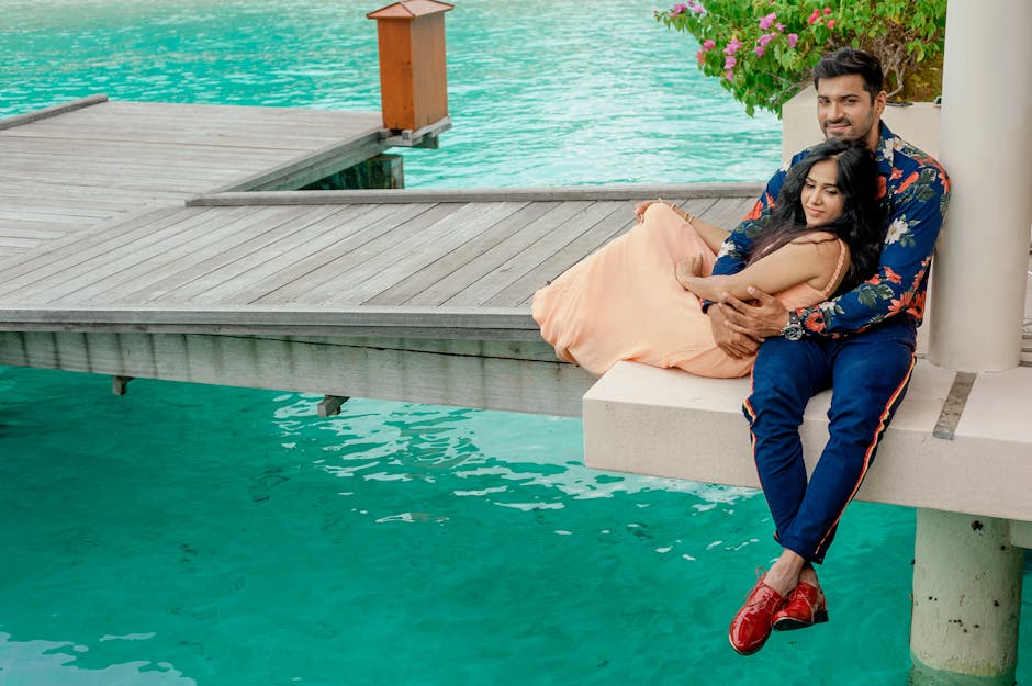Couple embracing by a serene Maldives pier, capturing romance and tropical getaway vibes